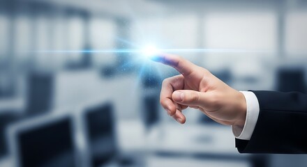 A hand in a suit touching a bright light in a blurred office environment with computers visible