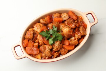 Delicious cooked stew in baking dish on white marble table, top view