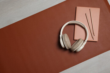 Headphones, notebook, pencils and brown mat on light grey table, flat lay. Space for text