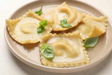 Delicious ravioli with basil on light table, closeup