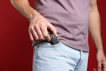 Man with hidden spy camera in his pocket on red background, closeup