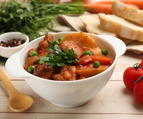 Delicious cooked stew served on light wooden table, closeup