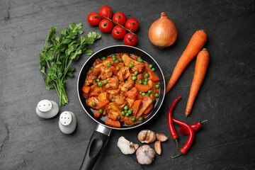 Delicious cooked stew in frying pan and ingredients on black table, flat lay