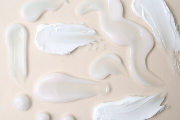 Samples of moisturizing creams on beige background, flat lay