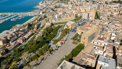 Fototapeta premium Aerial view of Piazza Scandallato, located in the historic center of Sciacca, in the province of Agrigento, Sicily, Italy. The tree-lined square overlooks the Mediterranean Sea.