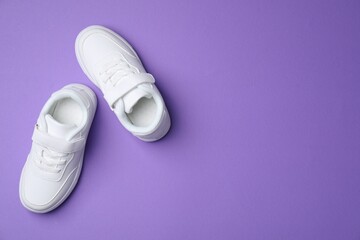 Stylish kid's sneakers on violet background, flat lay. Space for text
