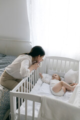 mom puts the baby to sleep by rocking him, mom holds the baby in her arms gently hugging and kissing him, mother and child, healthy sleep of the child with the mother.