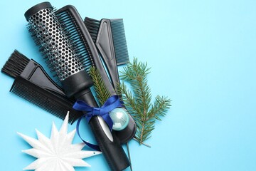 Hairdresser's tools and fir tree branches on light blue background, flat lay with space for text....