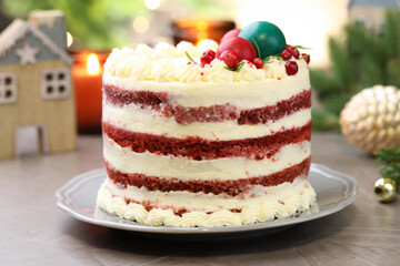 Delicious sponge cake with Christmas decor and red currants on grey textured table against blurred lights, closeup. Bokeh effect