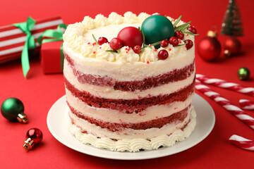 Delicious sponge cake with Christmas decor and berries on red background, closeup