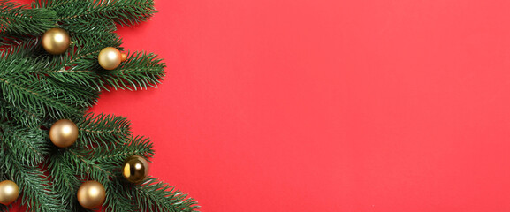 Christmas tree branches with baubles on red background, flat lay. Space for text