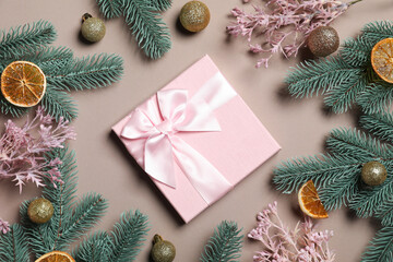 Christmas tree branches with festive decor and gift box on beige background, flat lay