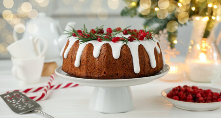 Tasty Christmas cake with icing, cranberries and rosemary on white wooden table, closeup
