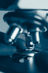 High-quality close-up image of a laboratory microscope being adjusted by a scientist in gloves. Represents science precision, healthcare innovation, and biotechnology research.