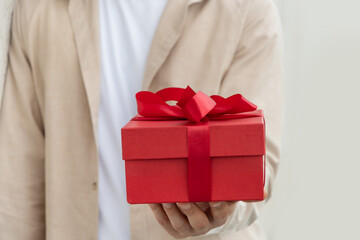 Red gift box with bow-knot in mans hand. Present with love for Birthday or Valentine's Day....