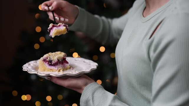 Cozy Christmas scene with cake slice and festive blue mug on table, warm bokeh lights in background