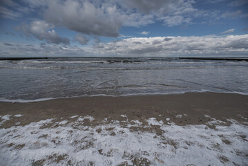 WINTER TIME - Snow on the sea beach and cumulus clouds over the sea
