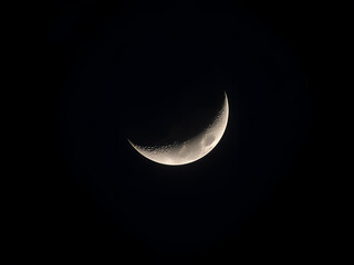 Thin crescent moon glowing softly in dark night sky creating serene and minimalist astronomy landscape scene