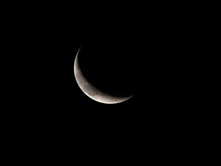 Thin crescent moon glowing softly in dark night sky creating serene and minimalist astronomy landscape scene