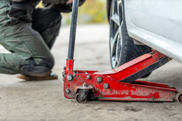 Fototapeta premium Car lifted with hydraulic floor jack