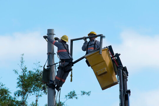 Equipe de manuten&ccedil;&atilde;o da constru&ccedil;&atilde;o civil fazendo troca de fios da rede el&eacute;trica, em cima do guindaste realizado troca de equipamentos de alta tens&atilde;o