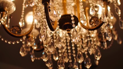 A close-up shot showcases the intricate design of a crystal chandelier with a warm golden hue - Powered by Adobe