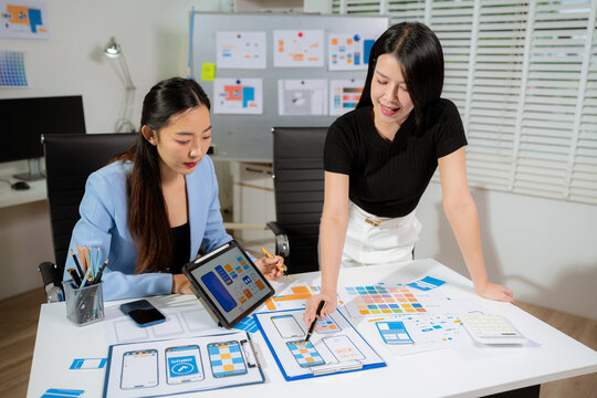 UX developer and ui designer brainstorming about mobile app interface wireframe design with customer breif and color code at office.