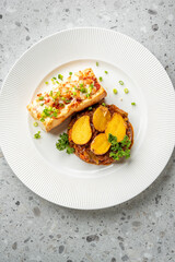 A beautifully plated restaurant-quality meal featuring slow-cooked beef stew topped with roasted potato halves and fresh parsley, served with a side of toasted baguette with toppings.
