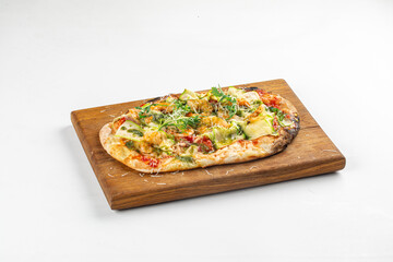 Freshly baked vegetable pizza with cheese, zucchini, and herbs served on wooden board over white background