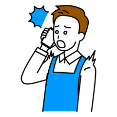 スマートフォンでの通話で驚くエプロン姿の男性