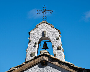 Cross and bell tower of the chapel on the Gornergrat in the canton of Valais on a sunny autumn day with blue sky, Switzerland