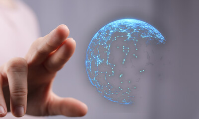 Abstract image showing hand touching a digital network or globe representing connectivity, global communication, and technology.