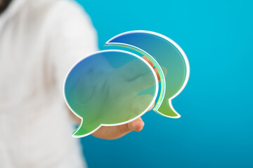 Hand holding speech bubbles representing communication, online chat, social media, discussion, and connection. Concept of talking, sharing ideas