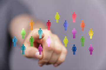 Visual of a hand pointing at a group of colorful human icons, symbolizing teamwork, diversity, and connection. Concept of networking and busines