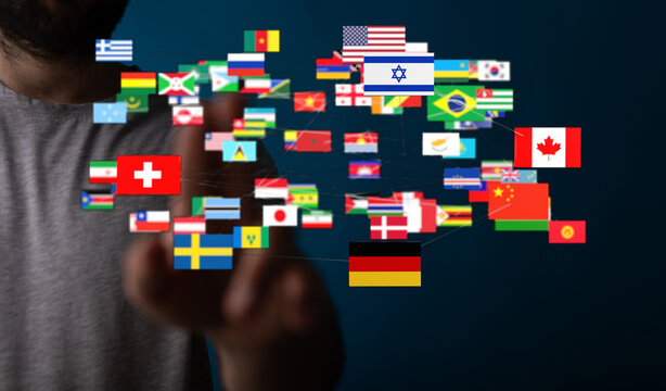 Human hand pointing towards a collection of international flags symbolizing global connection and unity. Concept of world peace and communicatio