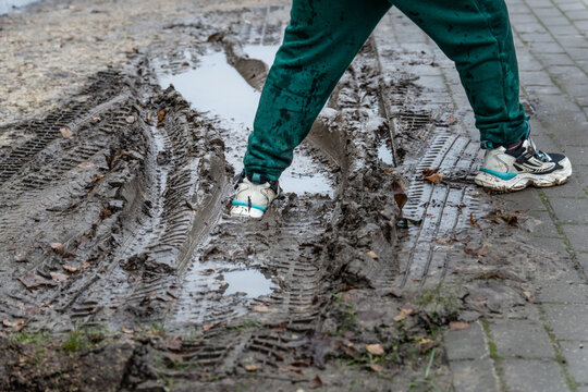 Walking Through Muddy Puddle After Rain — Dirty Sneakers and Tire Tracks Symbolizing Real Life and Imperfection
