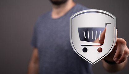 Person points at a shield featuring shopping cart icon representing online shopping security...
