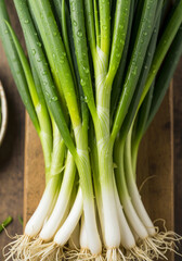 Obraz premium Fresh Raw Organic Green Onions Bunch of Scallions Displayed on Wooden Surface with Water Droplets, Healthy Vegetable Food.
