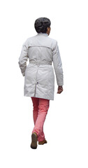 femme senior vue de dos portant un imperméable beige et un pantalon corail, marchant tranquillement, cheveux courts gris, chaussures marron, saison automnale
