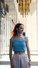 Obraz premium A portrait of a teenage girl with red hair posing for a photo near columns at the entrance to a business center