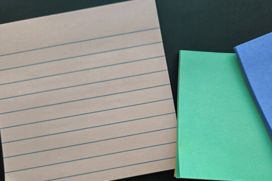 Blank ruled notebook paper and sticky notes background banner isolated on slate blackboard with clean horizontal lines for text overlays, ideal for educational or office projects.