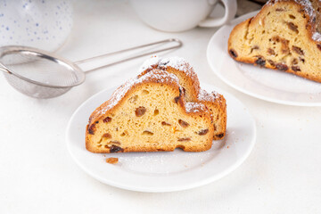 Traditional European Christmas fruitcake pastry, fragrant home baked stollen, with spices and dried fruit. Sliced on white table with xmas tree branches and decorations, copy space