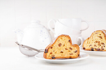 Traditional European Christmas fruitcake pastry, fragrant home baked stollen, with spices and dried fruit. Sliced on white table with xmas tree branches and decorations, copy space