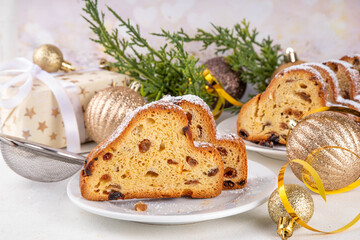 Traditional European Christmas fruitcake pastry, fragrant home baked stollen, with spices and dried fruit. Sliced on white table with xmas tree branches and decorations, copy space