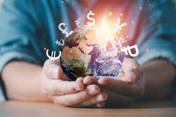 Close-up of hands holding a glowing Earth with global currency symbols representing international finance economy money exchange rate and transfer forex investment concept.