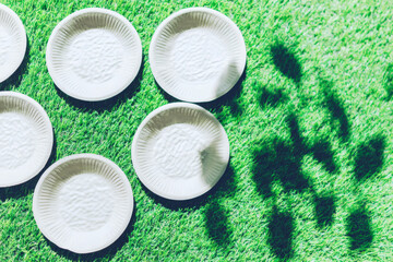  Minimal composition of compostable plates lying on green grass. Eco-friendly concept of sustainable living, clean photography with space for copy