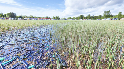 Wide shot of wetland marsh polluted with floating plastic trash. Natural lighting and open sky create balance between beauty and decay. Ideal for environmental projects, ecological posters, or sustain