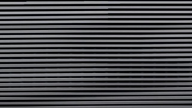 Close-up of horizontal metal slats in a repeating pattern. Grey and black contrast