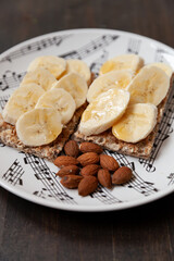 Crispy bread with sliced banana arranged on a plate with a almond