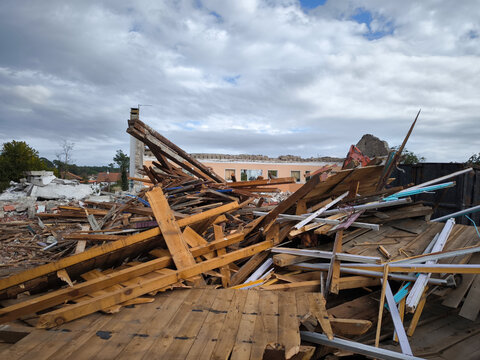 Pilha de escombros de madeira despeda&ccedil;ada e algumas vigas e peda&ccedil;os de bet&atilde;o mais ao fundo ap&oacute;s a demoli&ccedil;&atilde;o de um edif&iacute;cio, com restos de uma estrutura ainda vis&iacute;vel mais &agrave; frente